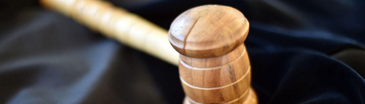 Auf einem Tisch im Landgericht Karlsruhe liegt ein Richterhammer aus Holz, darunter liegt eine Richterrobe. 