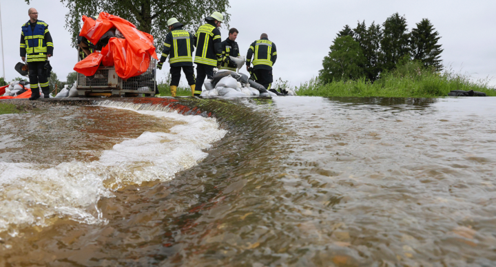 Einsatzkräfte der Feuerwehr errichten am Nonnenbach in Bad Saulgau im Ortsteil Moosheim einen Damm mit Sandsäcken gegen das Hochwasser.