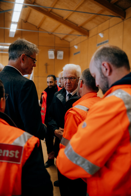 Bundesverkehrsminister Patrick Schnieder (links) und Ministerpräsident Winfried Kretschmann (Mitte) im Gespräch mit Einsatzkräften