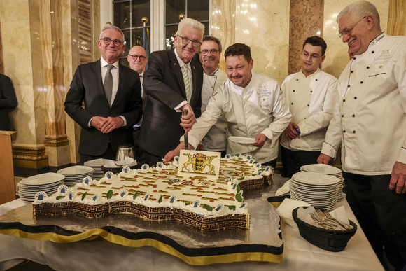 Ministerpräsident Winfried Kretschmann (Mitte) und Innenminister Thomas Strobl (links) beim Anschnitt einer großen Baden-Württemberg-Torte 