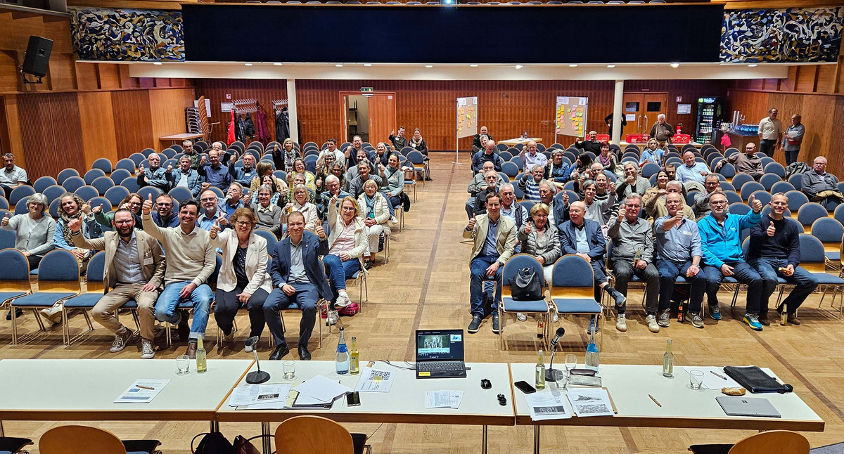 Bürgerinnen und Bürger der Gemeinde Waldbronn sitzen auf Stühlen und zeigen den Daumen nach oben.