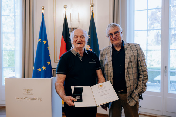 Kunststaatssekretär Arne Braun (rechts) und Erich Schmeckenbecher (links) mit der Staufermedaille und der Verleihungsurkunde.