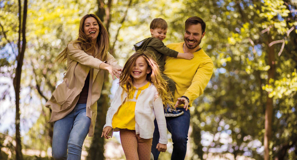 2 Kinder und 2 Erwachsene fröhlich im Wald