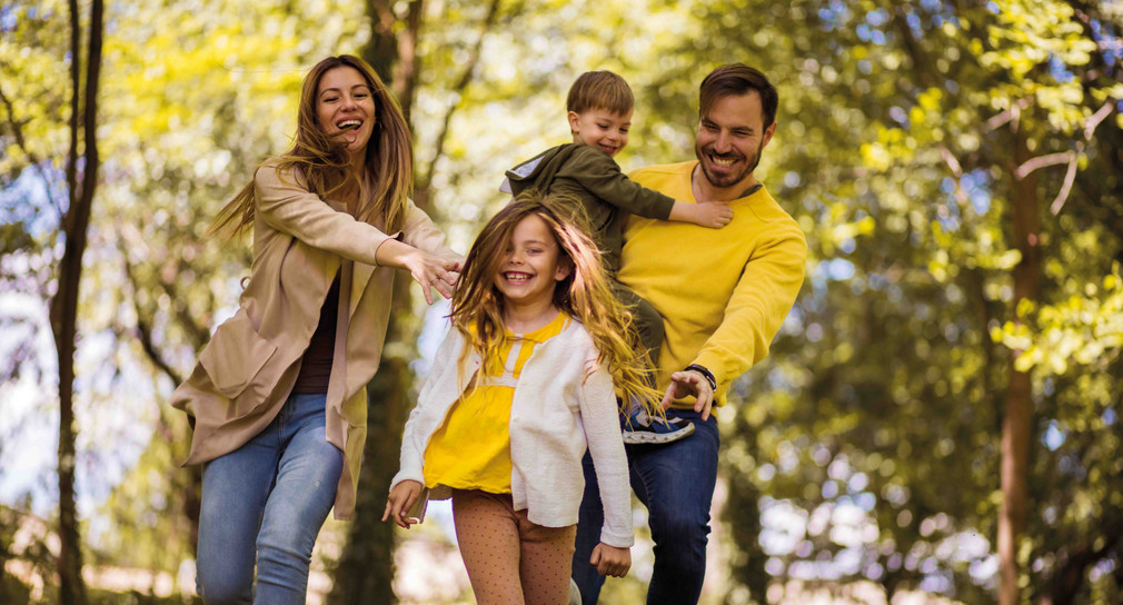 2 Kinder und 2 Erwachsene fröhlich im Wald