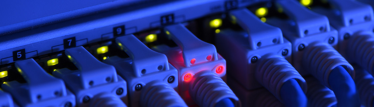 Ein Netzwerk-Kabelstecker leuchtet in der Netzwerkzentrale einer Firma zu Kontrollzwecken rot. (Bild: picture alliance/Felix Kästle/dpa)