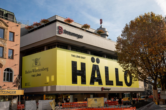 Fassade mit der Aufschrift „Baden-Württemberg - THE LÄND“ unter dem Landeswappen sowie „THE LÄND sagt HÄLLO“ am Kaufhaus Breuninger in Stuttgart