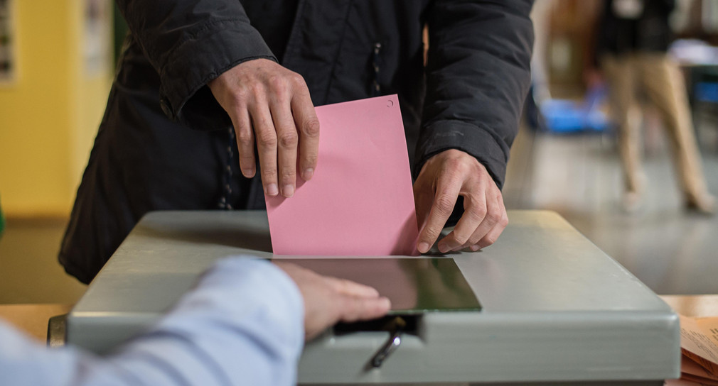 Ein Mann wirft seinen Stimmzettel in die Wahlurne. (Bild: Wolfram Kastl / dpa)