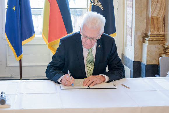 Ministerpräsident Winfried Kretschmann (Mitte) unterzeichnet den Gesellschaftsvertrag für die Zukunft der Landwirtschaft und der biologischen Vielfalt in Baden-Württemberg.