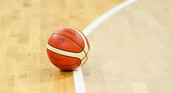 Ein Basketball liegt auf dem Boden einer Turnhalle.