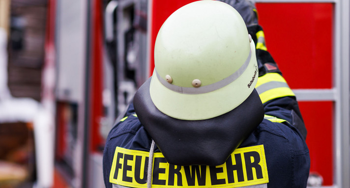 Ein Feuerwehrmann holt während einer Einsatzübung einer Freiwilligen Feuerwehr eine Leiter vom Dach eines Einsatzfahrzeugs.