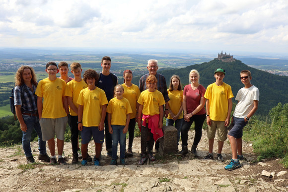 Gruppenbild mit Ministerpräsident Winfried Kretschmann (M.) und der Schwäbischen Albvereinsjugend auf dem Zeller Horn, im Hintergrund die Burg Hohenzollern 
