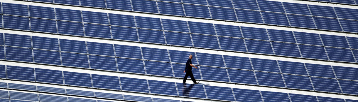 Ein Techniker läuft über ein Dach, auf dem eine Photovoltaik-Anlage montiert wurde. (Bild: © picture alliance/Jens Büttner/dpa-Zentralbild/dpa)