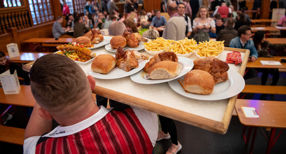 Kellner im Festzelt des Cannstatter Wasen trägt Speisen