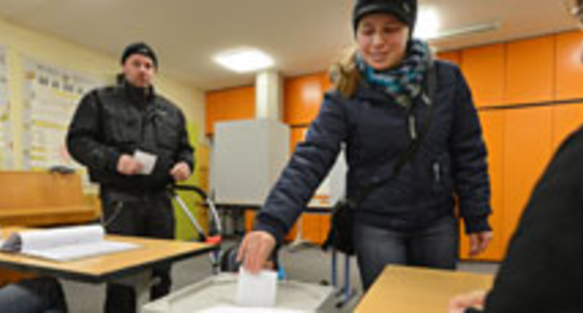 Eine Bürgerin wirft ihren Stimmzettel in die Urne (Bild: dpa).