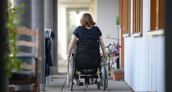 Eine Rollstuhlfahrerin fährt in einer Wohnanlage zu ihrer Wohnung. (Foto: © dpa)