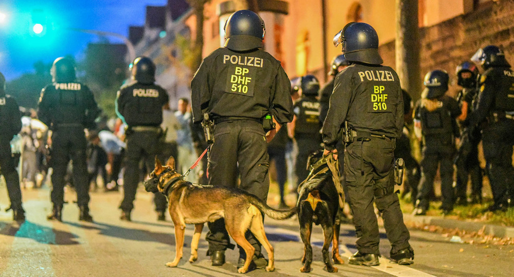 Einsatzkräfte der Polizei stehen mit Hunden nach Ausschreitungen bei einer Eritrea-Veranstaltung auf der Straße.