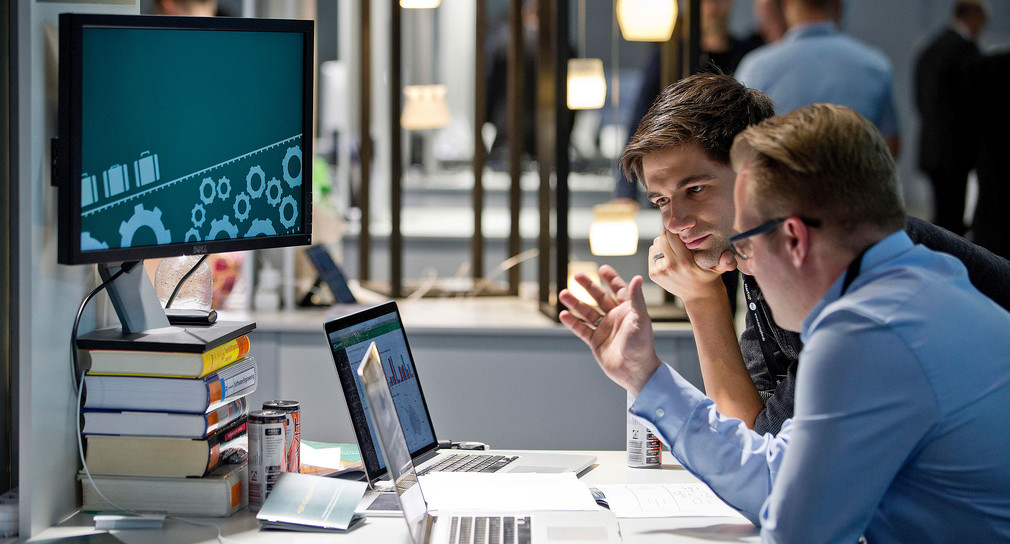 Zwei Personen unterhalten sich vor einem Laptop auf dem Start-up-Gipfel.