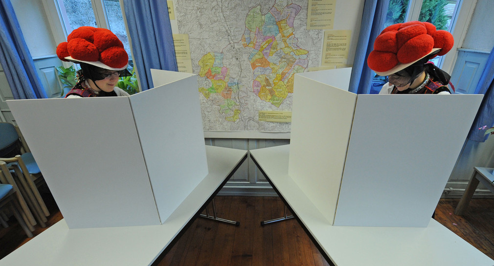 Zwei Frauen in Tracht und Bollenhut bei der Stimmabgabe im Wahllokal (Bild: dpa).