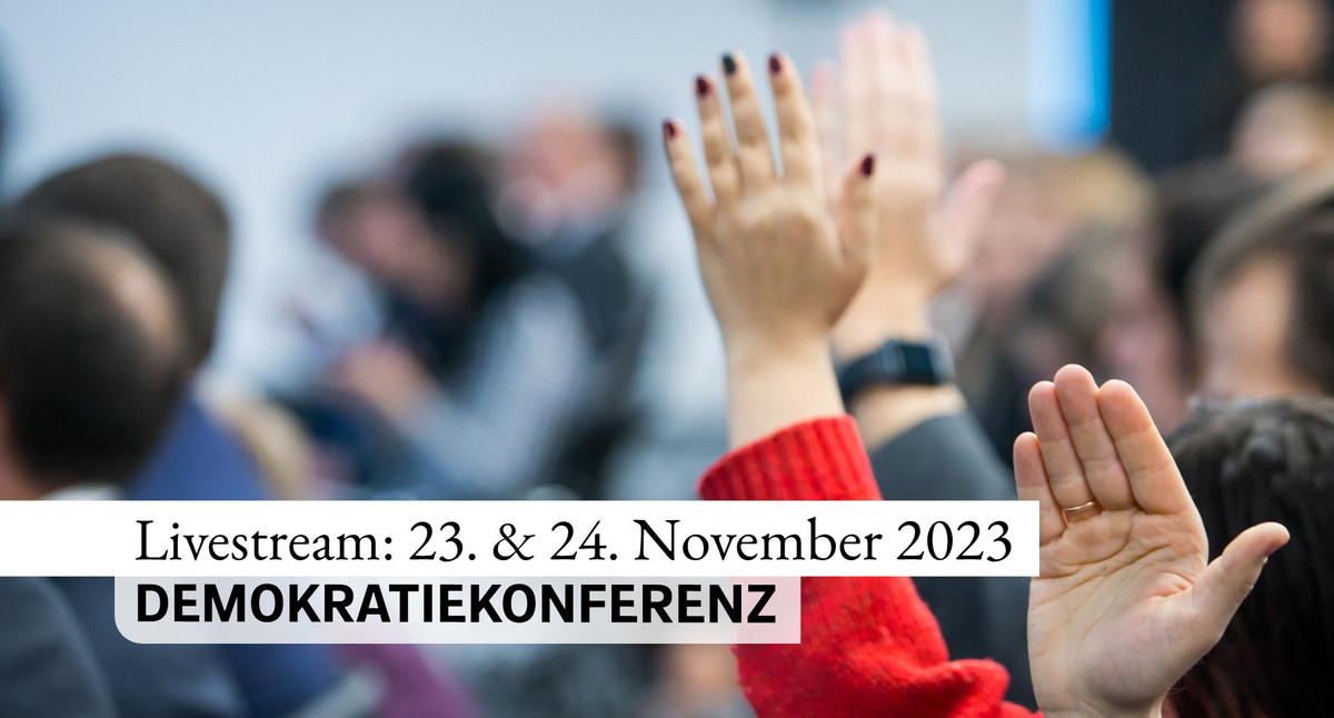 Menschen in einer Konferenz, dazu der Schriftzug „Livestream: 23. und 24. November 2023, DEMOKRATIEKONFERENZ“.