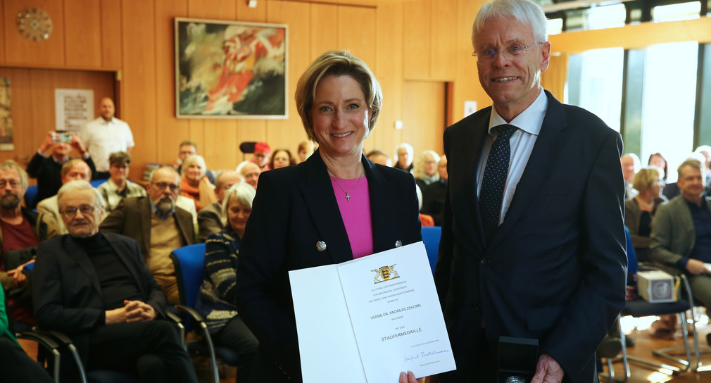 Auf dem Bild ist Ministerin Dr. Nicole-Hoffmeister-Kraut mit Herrn Dr. Andreas Zekorn zu sehen. Beide lächeln in die Kamera. Die Ministerin hält eine Urkunde in beiden Händen. 
