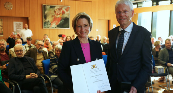 Auf dem Bild ist Ministerin Dr. Nicole-Hoffmeister-Kraut mit Herrn Dr. Andreas Zekorn zu sehen. Beide lächeln in die Kamera. Die Ministerin hält eine Urkunde in beiden Händen.