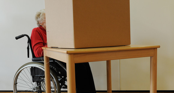 Eine Wählerin im Rollstuhl gibt in einem Wahllokal ihre Stimme ab. (Bild: picture alliance/Angelika Warmuth/dpa)