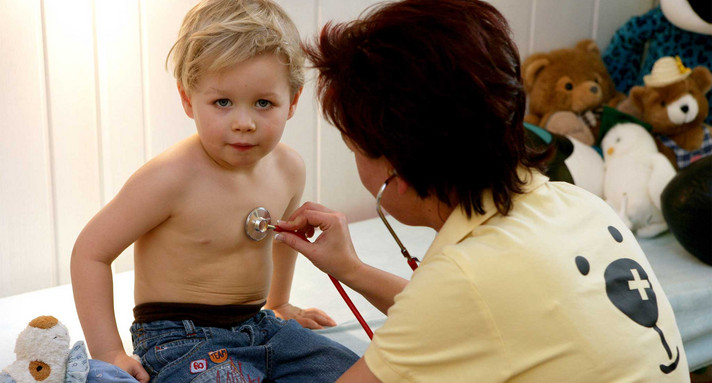 Eine Kinderärztin untersucht einen kleinen Jungen mit einem Stethoskop (Bild: © dpa). 