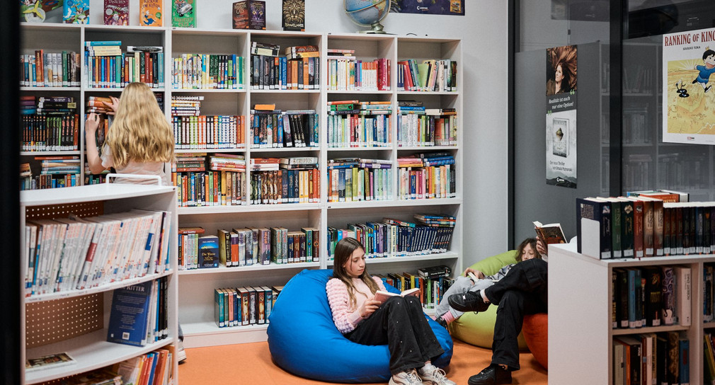 Zwie Kinder sitzen in einer Bücherei auf Sitzsäcken und lesen