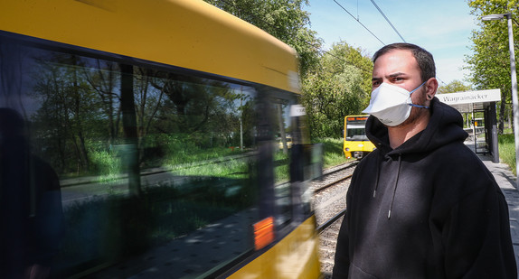 Symbolbild: Ein junger Mann trägt vor einer einfahrenden Stadtbahn in Stuttgart eine Atemschutzmaske. (Bild: picture alliance/Christoph Schmidt/dpa)