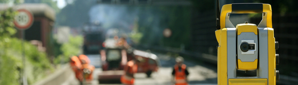 Ein Vermessungsgerät steht auf einer Autobahnbaustelle.