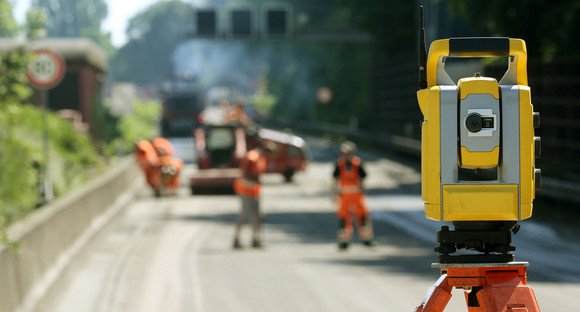 Ein Vermessungsgerät steht auf einer Autobahnbaustelle.