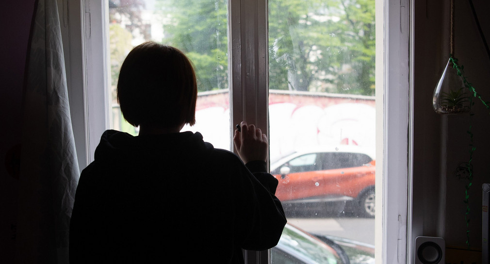 Eine Jugendliche schaut aus dem Fenster.