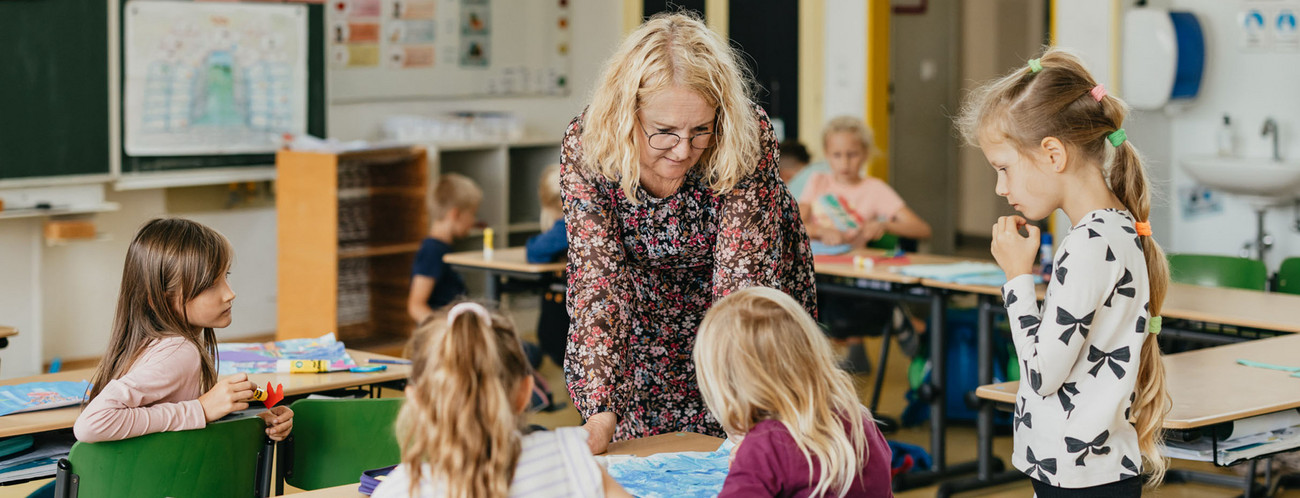 Eine Lehrerin mit Schülerinnen und Schülern in einem Klassenzimmer.