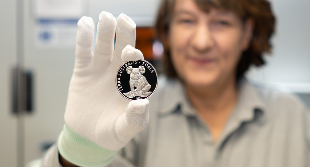 Staatssekretärin Gisela Splett hält die Vorderseite der frisch geprägten Medaille in die Kamera – das Koala Motiv ist zu erkennen.