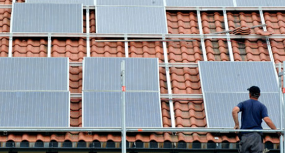 Ein Arbeiter installiert in St.Peter im Hochschwarzwald auf dem Dach eines Kleinunternehmens eine Solaranlage.