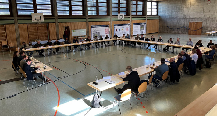 Die Teilnehmer der Dialogischen Themensammlung in Laichingen sitzen an Tischen in einem Quadrat in einer Sporthalle.