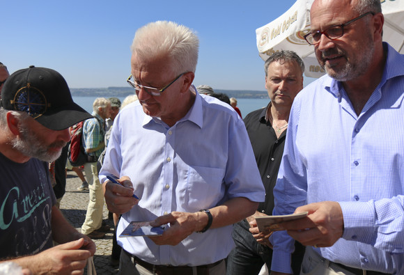 Ministerpräsident Winfried Kretschmann gibt einem Bürger ein Autogramm.