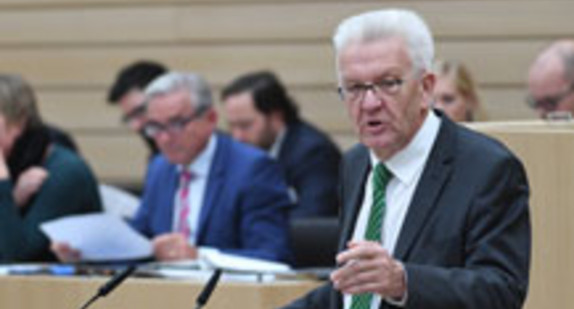 Kretschmann steht am Rednerpult im sanierten Landtag von Baden-Württemberg (Bild © dpa).