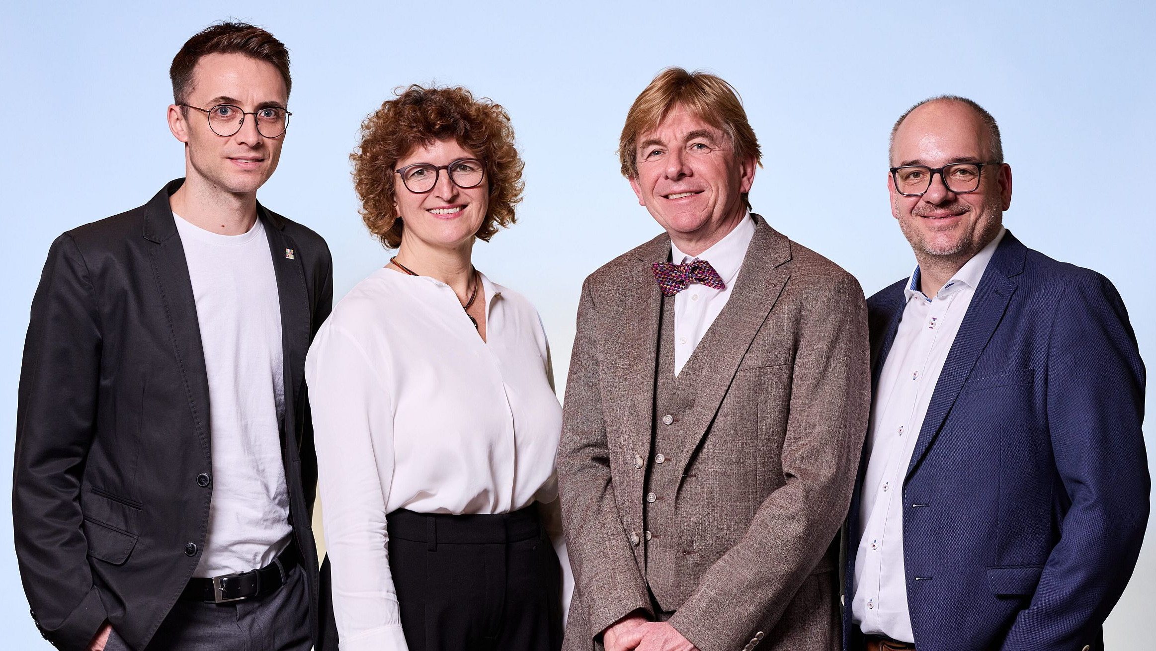 Drei M&auml;nner und eine Frau vor blauem Hintergrund