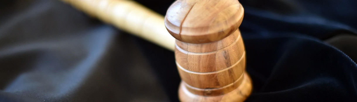 Auf einem Tisch im Landgericht Karlsruhe liegt ein Richterhammer aus Holz, darunter liegt eine Richterrobe. 