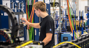 Ein Produktionstechnologe in Ausbildung arbeitet an einem Simulator f&uuml;r die Bewegungseinheit eines Laser. (Foto: &copy; dpa)
